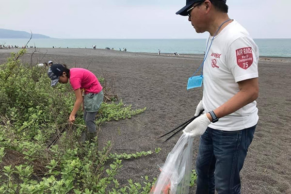 家族で海岸の清掃活動に参加する従業員